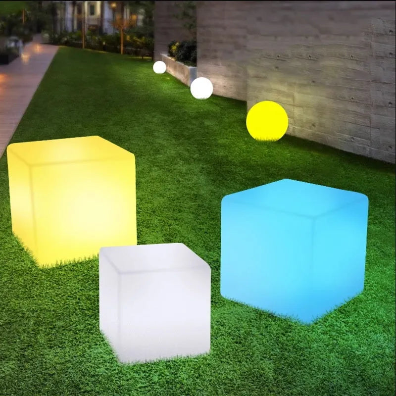 Modern square LED cube light stool in outdoor garden setting showing waterproof IP65 construction