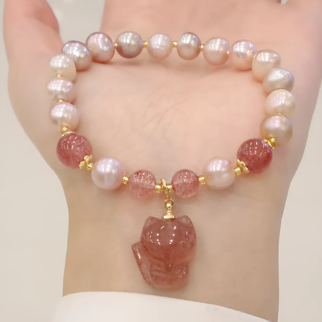 Women's light pink freshwater pearl bracelet with strawberry quartz beads and a small fox charm on an adjustable cord.