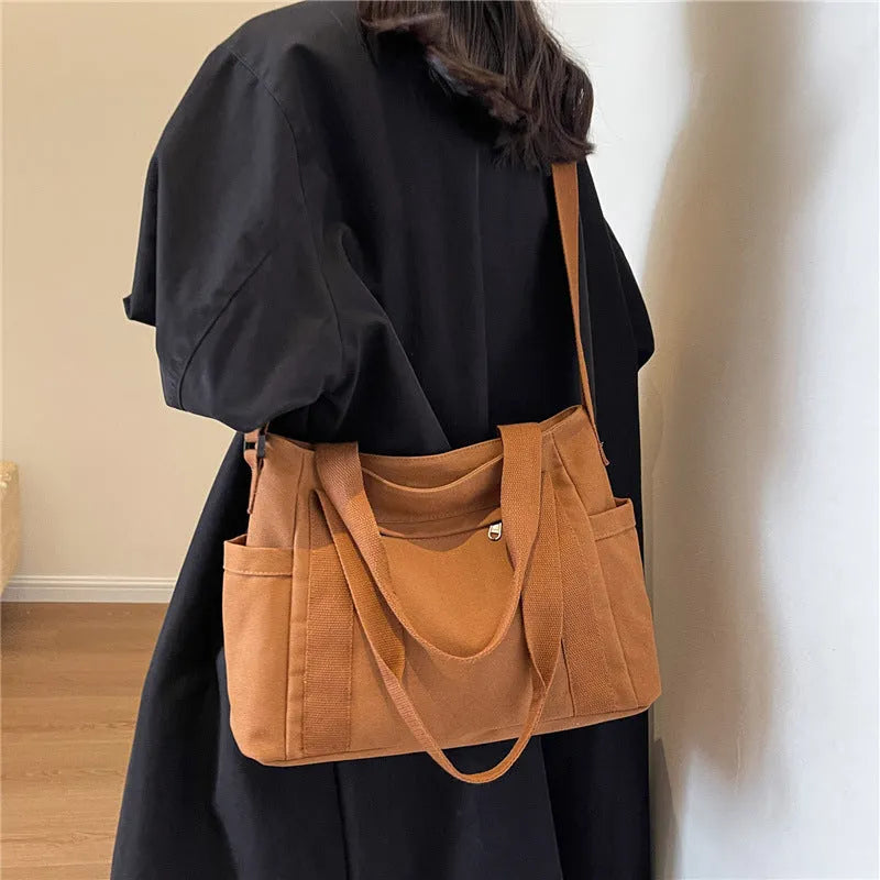 Polyester shoulder tote bag in solid colour with external sandwich pocket and internal phone pouch.