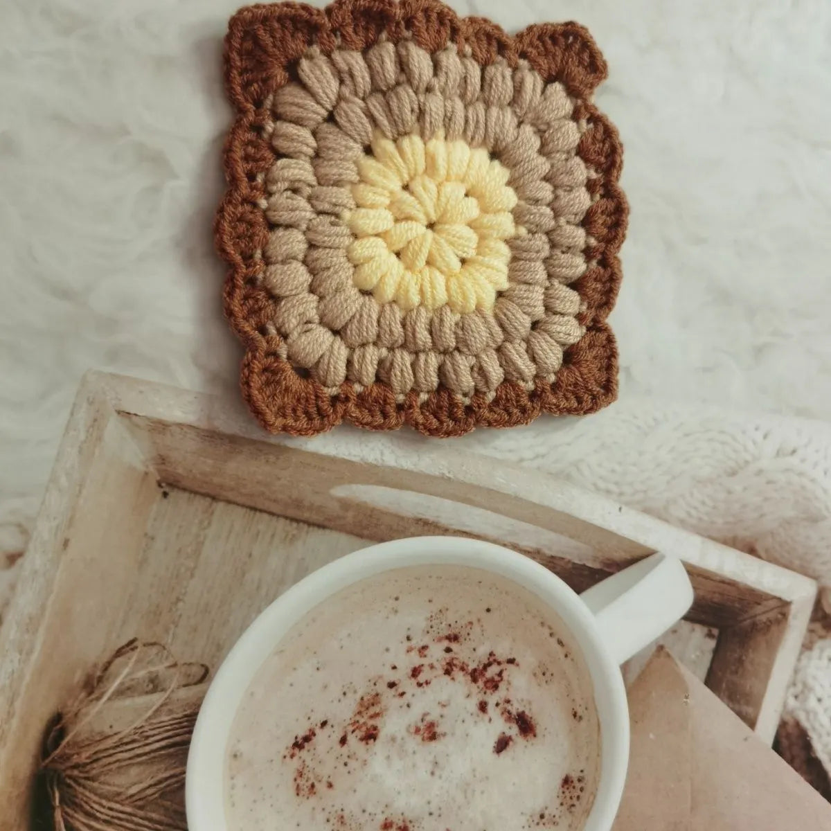 Crocheted wool cup placemat with grandmother lattice pattern in a choice of four colours.