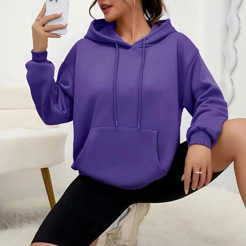 Women's loose grey drawstring hoodie with front pocket, shown in a casual setting.