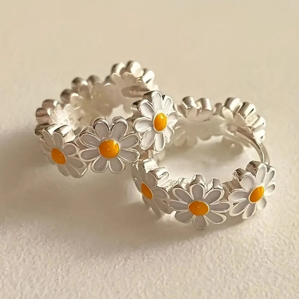 White daisy flower copper earrings with platinum gem accents on display