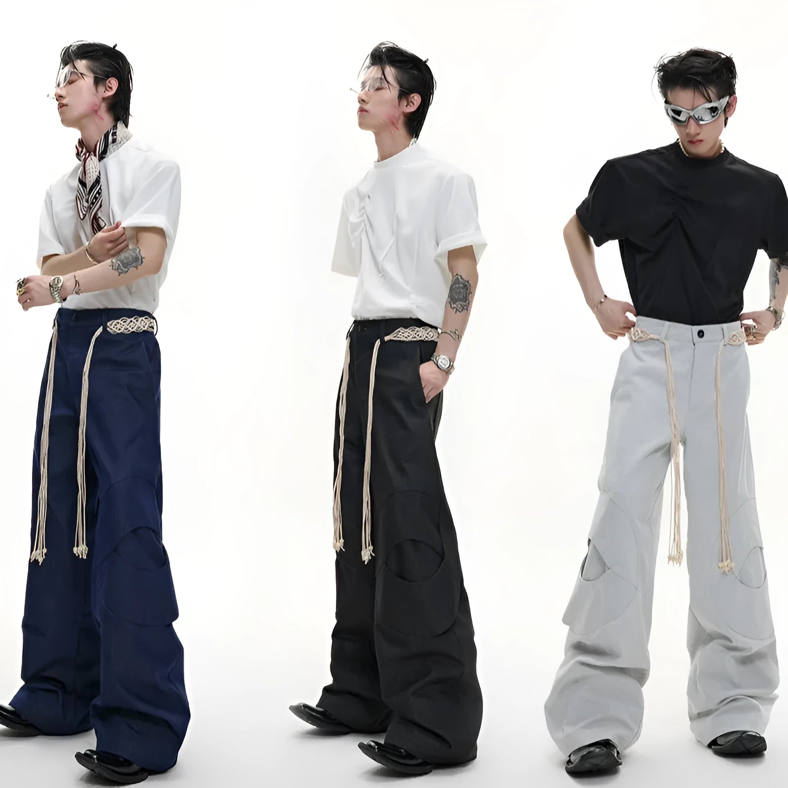 Men's dark coloured loose-fit straight-leg cotton trousers with decorative tassel and pocket zipper details.