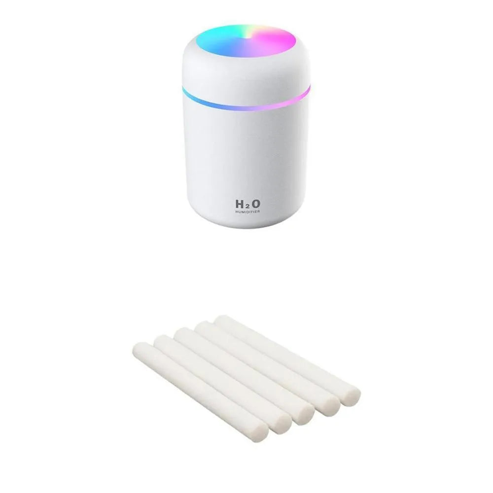 Pink USB desktop humidifier with LED lights emitting mist on a wooden desk