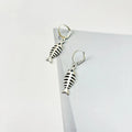 Close-up of silver fishbone pendant earrings on a white background, showing O-shaped chain detail.