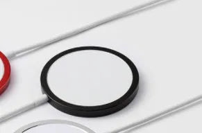 Silver metal magnetic wireless charger for iPhone on a wooden desk.
