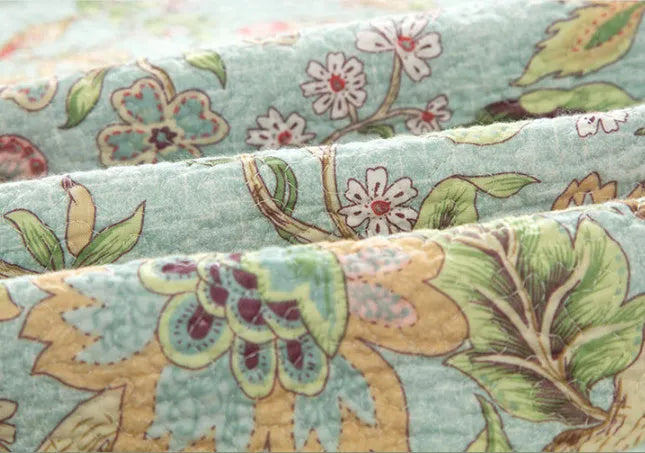 Blue American floral and bird pattern quilted cotton bedspread set laid on a bed.
