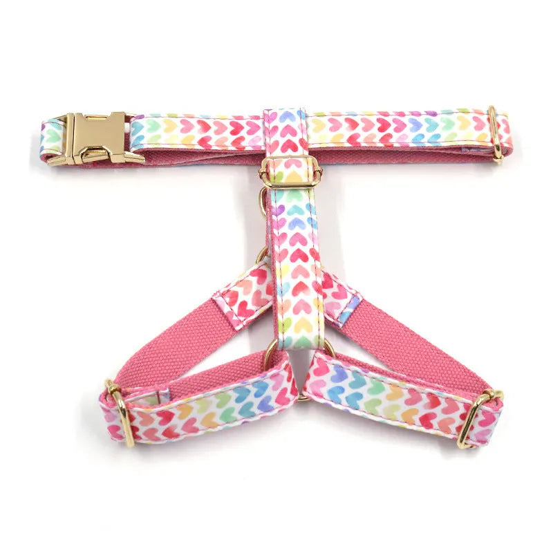 Pink dog harness with colourful heart-shaped stones and a gold-coloured buckle on a white background.