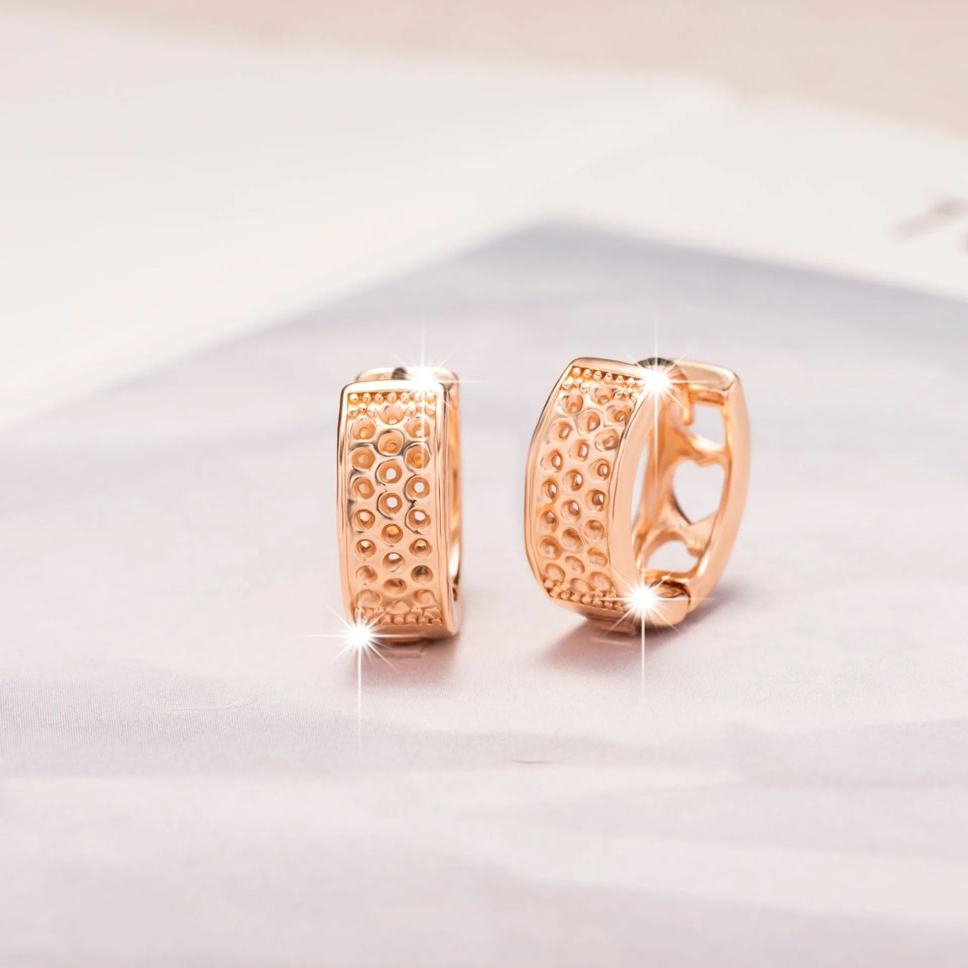 A pair of circular rose gold women's earrings with a three-heart hollowed-out design.