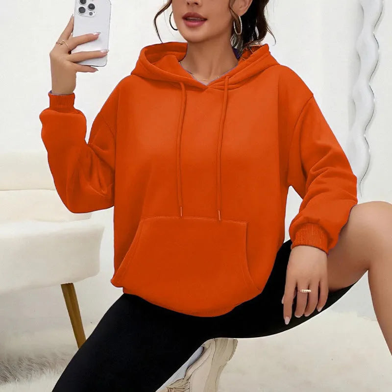 Women's loose grey drawstring hoodie with front pocket, shown in a casual setting.