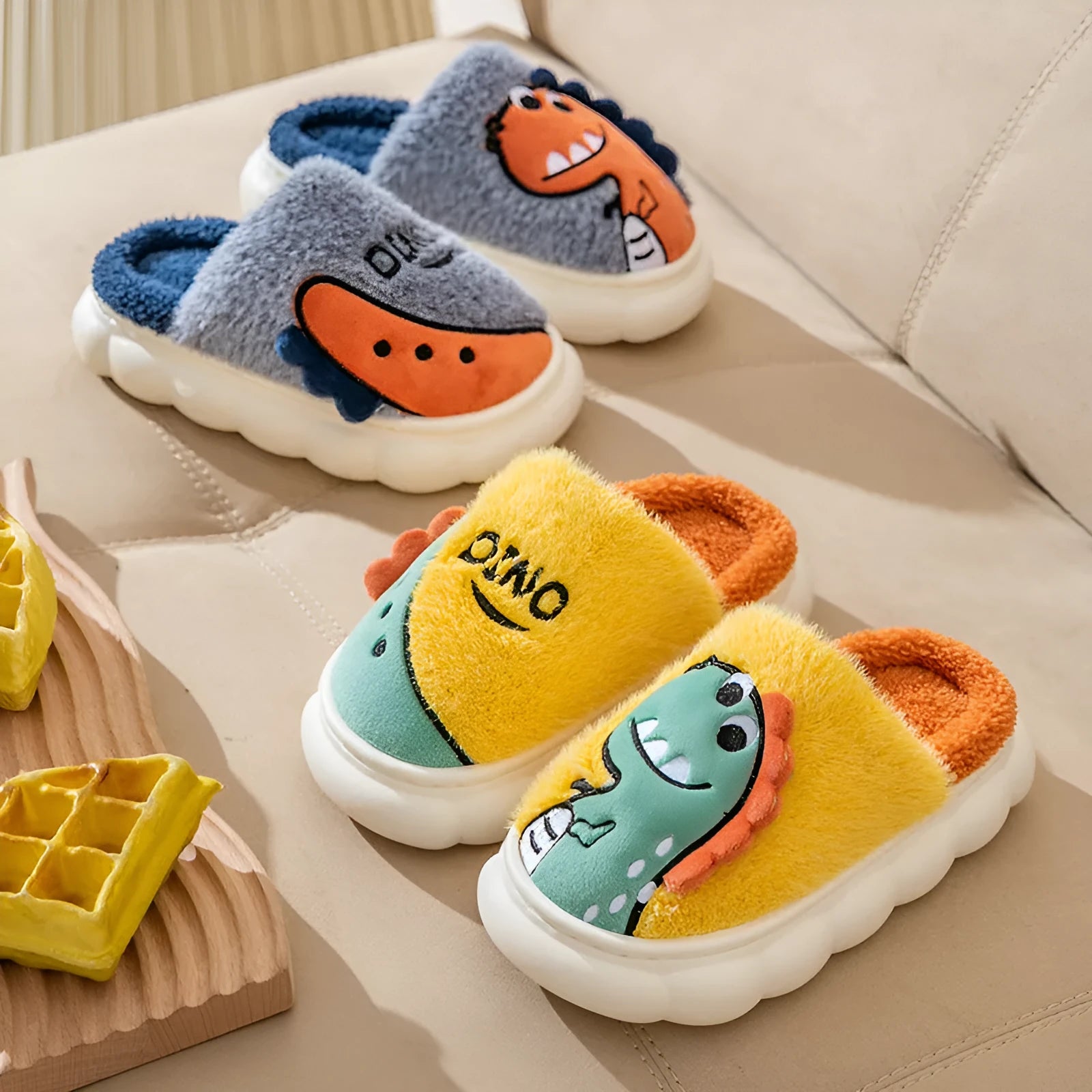 A pair of grey dinosaur print cotton slippers with plush lining, shown from above.