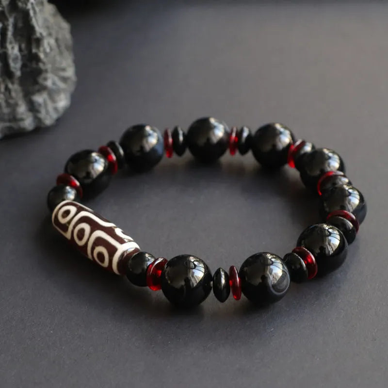 Black agate dzi bead bracelet with geometric 11mm beads on a hand-woven cord.