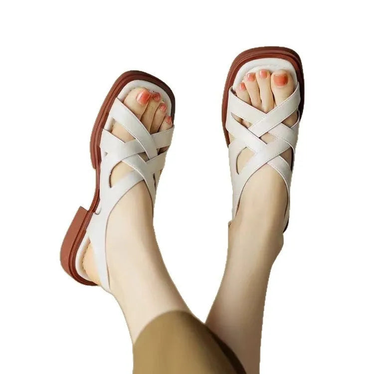 Women's black patent leather square toe beach sandals with cross strap design on a white background