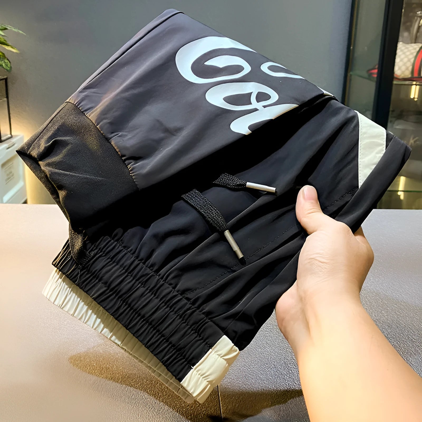 Men's solid black ultra-thin cotton cropped trousers with ankle banding on a casual model.