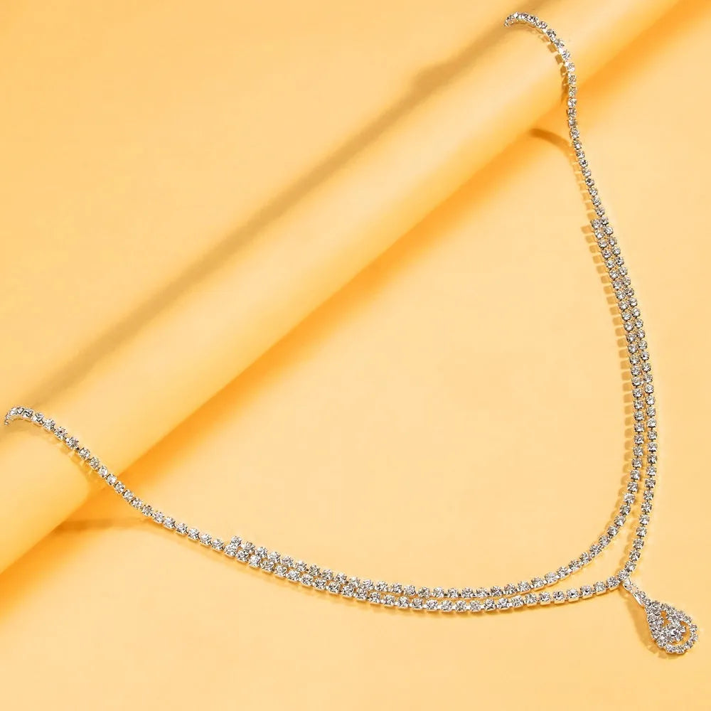 Gold rhinestone waist chain with water drop pendant and tassel on white background