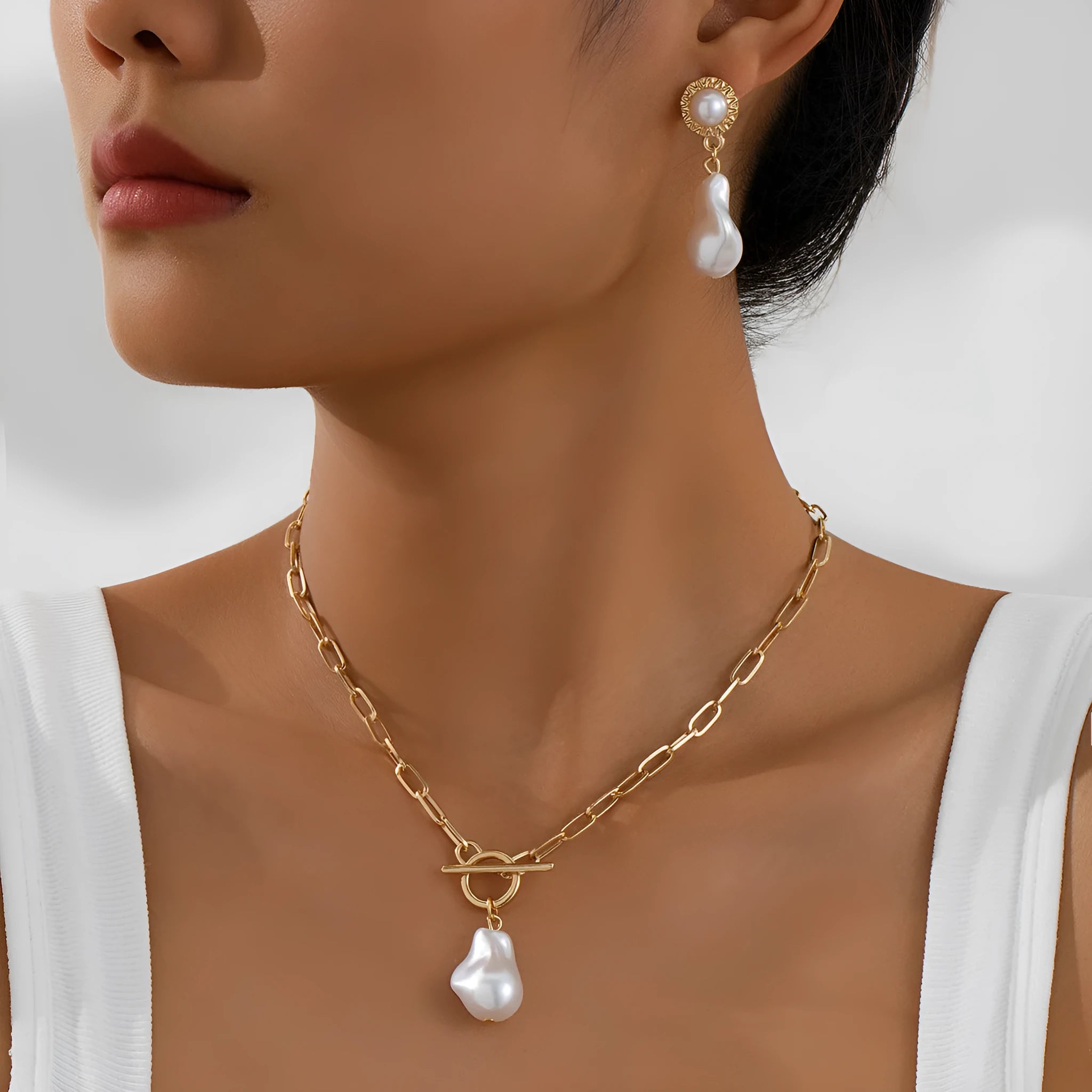 Gold tone baroque pearl pendant necklace and matching ear stud set on white background