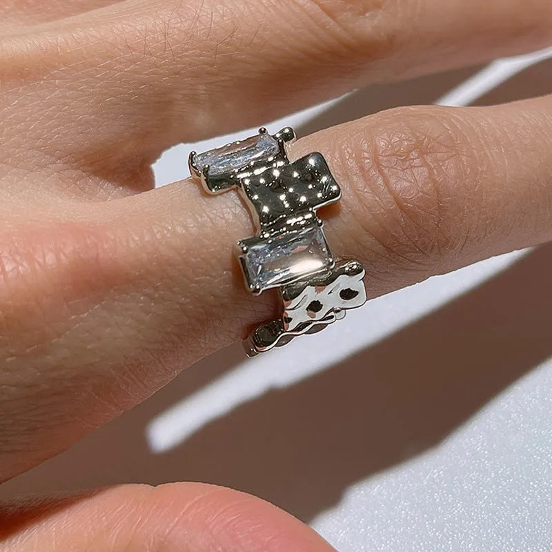 Silver geometric cross ring with open zircon stone setting.