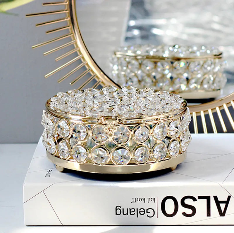 French gold metal jewelry box with a clear crystal glass lid and a lock, shown on a surface.