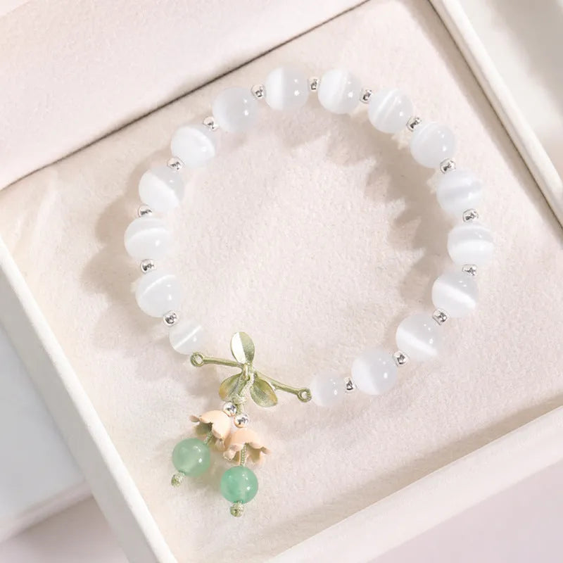 Women's opal cat's eye stone bracelet with diamond-shaped beads on wrist.