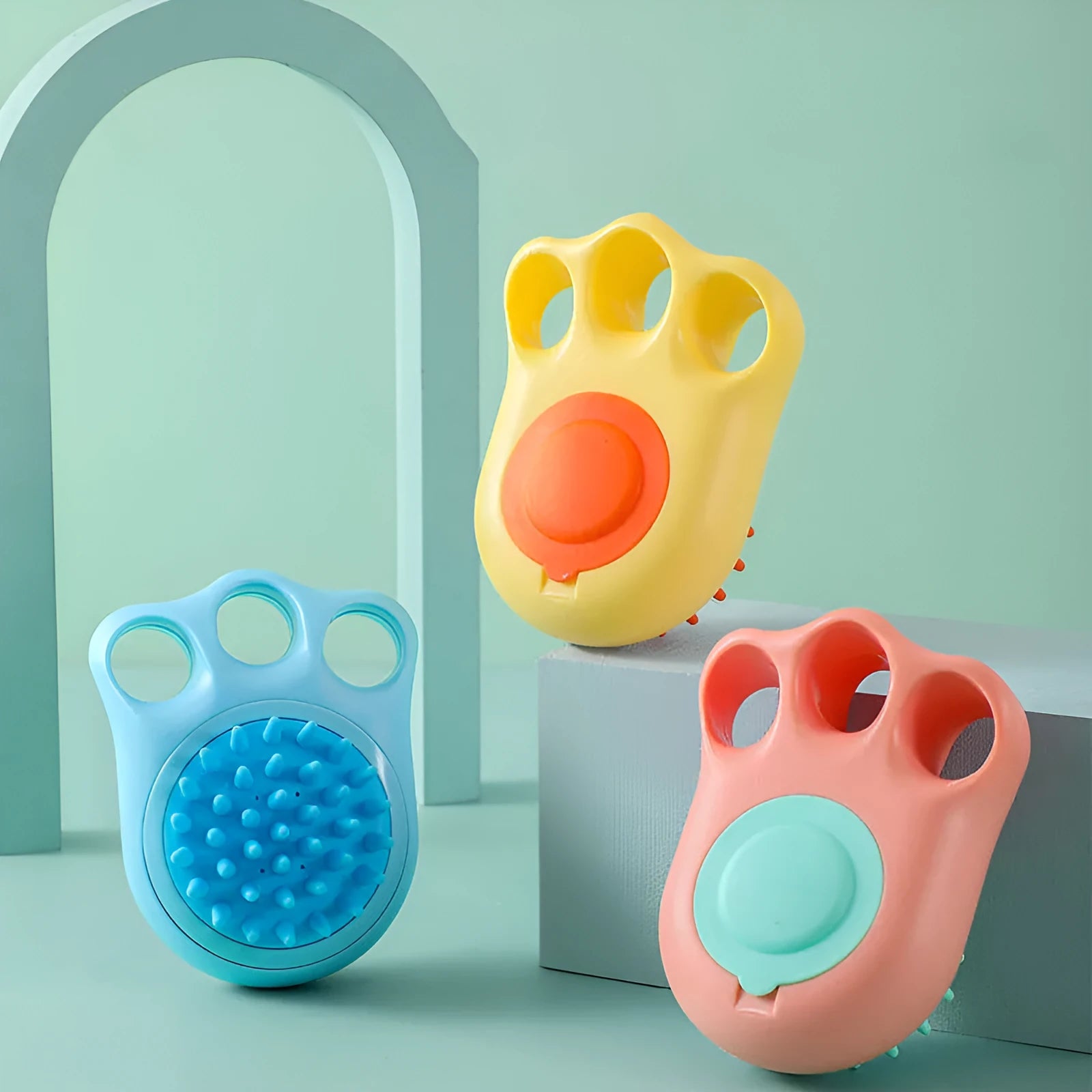 Multi-colour plastic pet bath brush with bristles on one side and a cat claw comb design on the reverse.