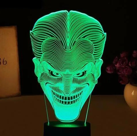 A 3D acrylic LED lamp with a square base, displaying one of its seven colour options on a desk.