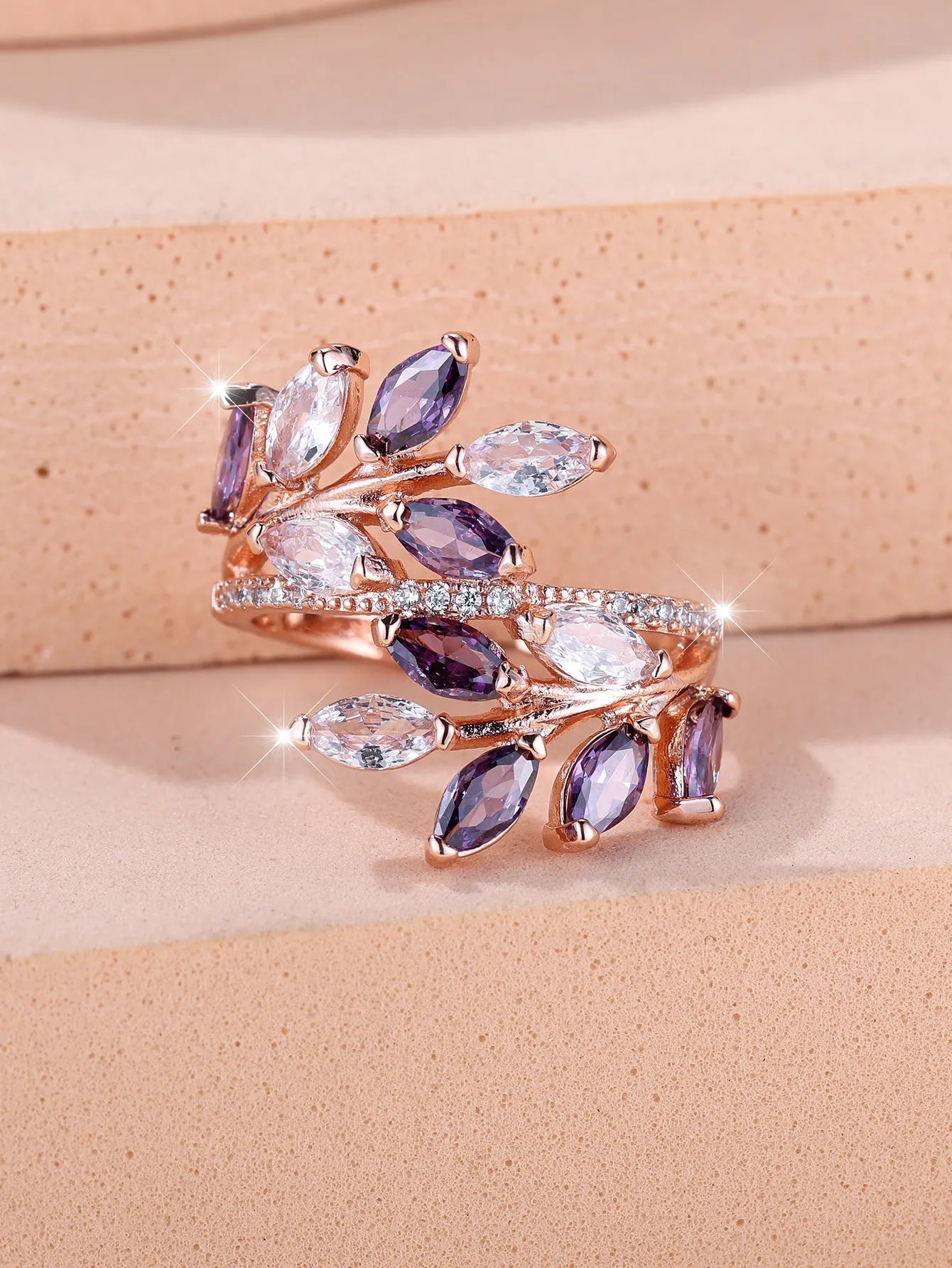 Adjustable copper leaf design ring with sparkling zircon stones on a model's finger.