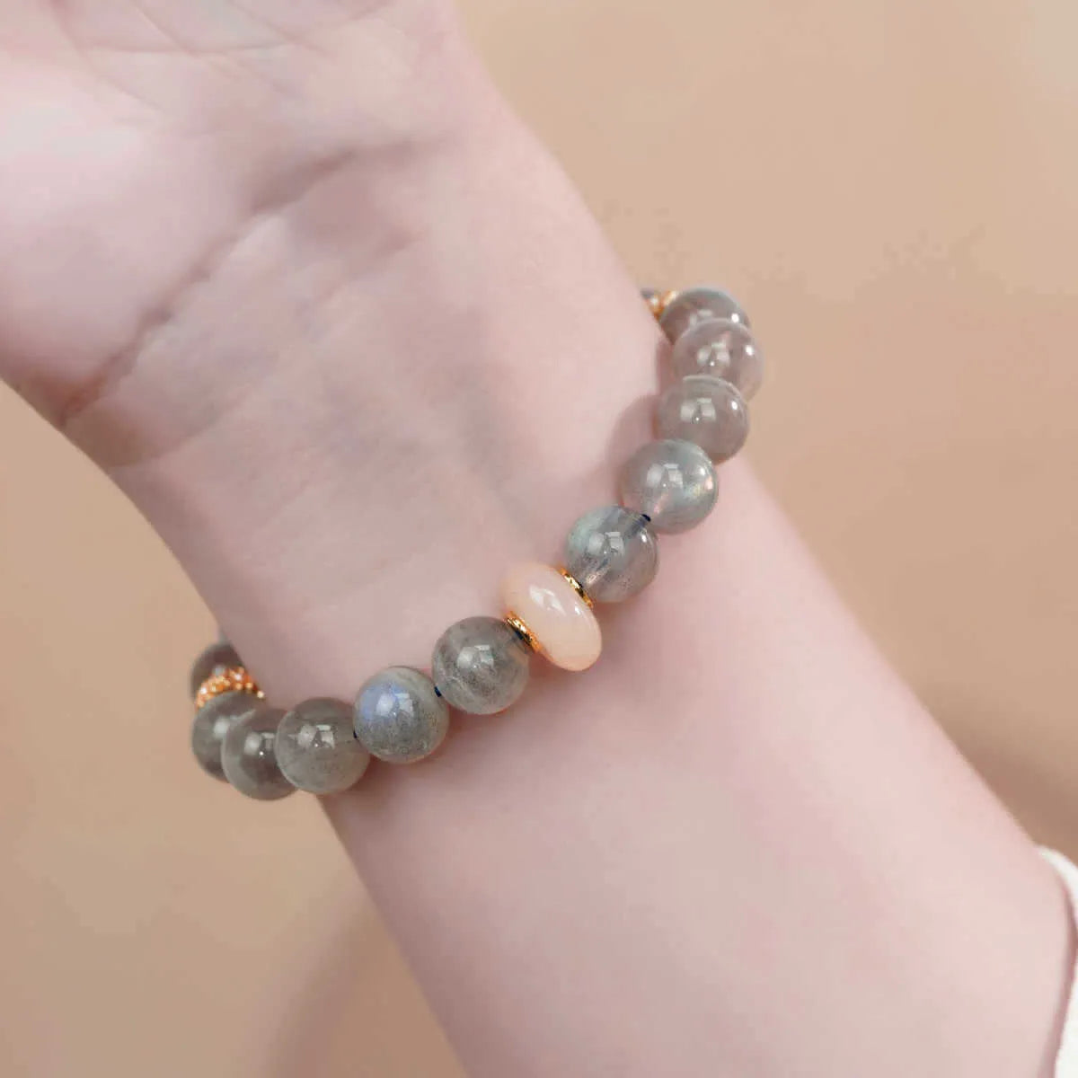 Grey moonstone bracelet with 8mm round beads on a wrist.
