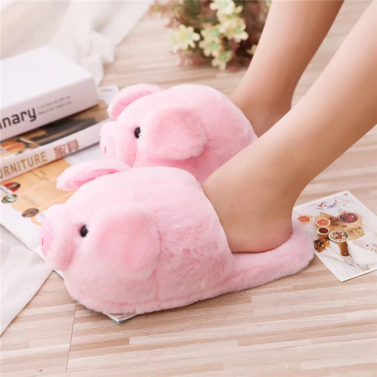 Pink pig-shaped plush floor slippers on a plain background.