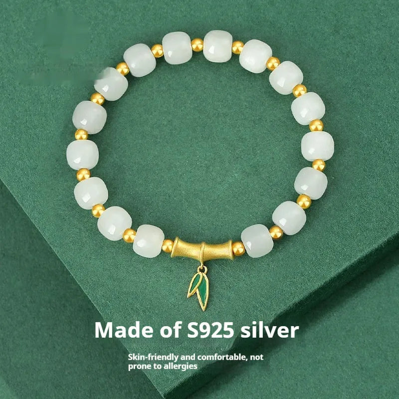 Women's bracelet with Hetian jade bead and sterling silver bamboo leaf charm on a wrist.
