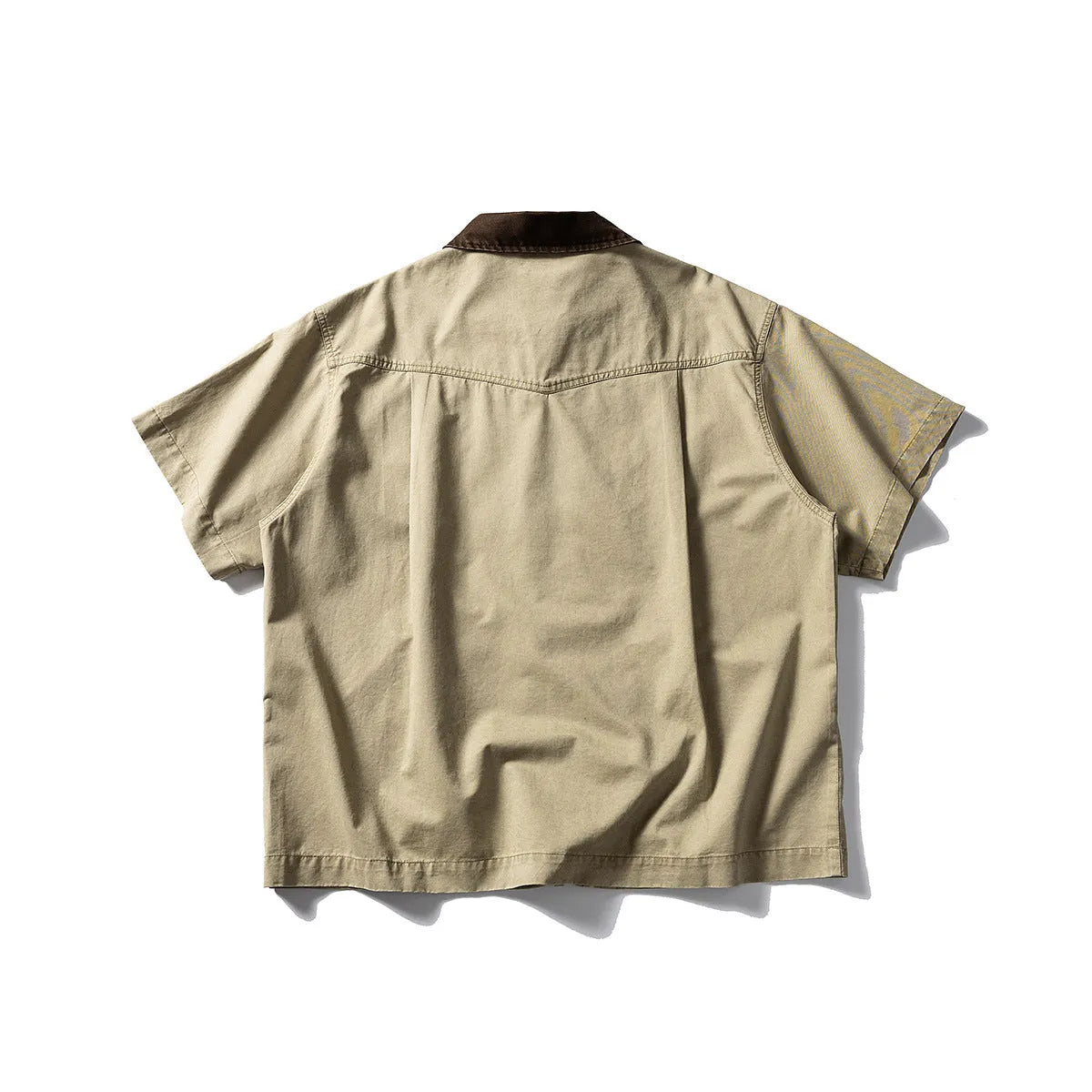 A khaki coloured, loose-fitting short sleeve cotton overalls shirt with a cardigan style on a hanger.