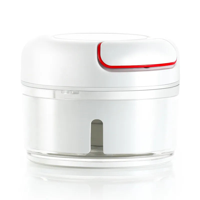 White manual food chopper with stainless steel blades on a magnet, shown with garlic and vegetables.
