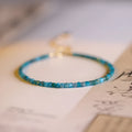 Women's blue and grey crystal bracelet with diamond faceted beads on a wrist.