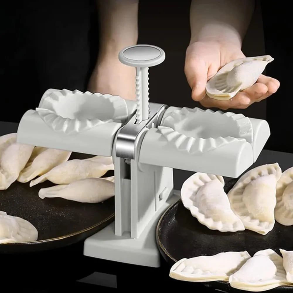 White double-head manual dumpling mould with stainless steel and plastic construction on a rubber anti-slip mat.