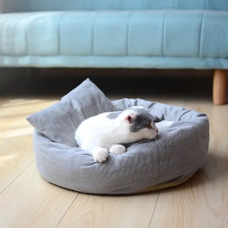 Grey round pet bed with raised rim and pillow for small dogs or cats on a wooden floor.