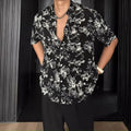 Man wearing a loose black short-sleeve shirt with a floral printed pattern.