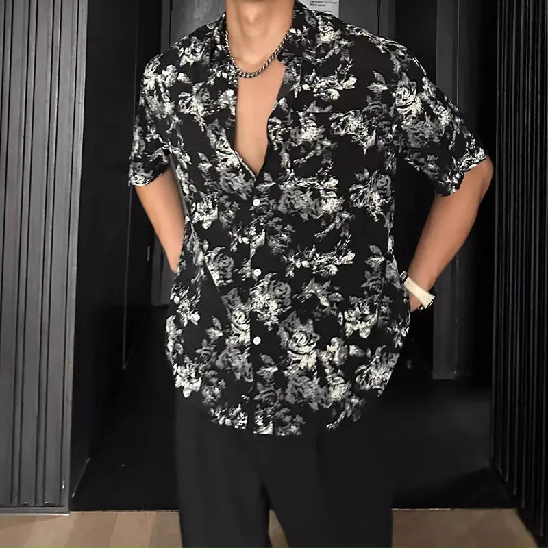 Man wearing a loose black short-sleeve shirt with a floral printed pattern.