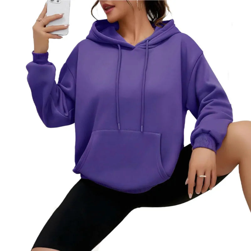 Women's loose grey drawstring hoodie with front pocket, shown in a casual setting.