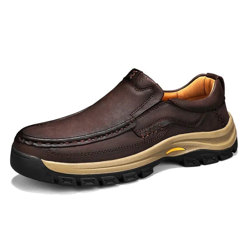 Men's black leather hiking shoes with thick rubber soles and round toe on a rocky outdoor path.