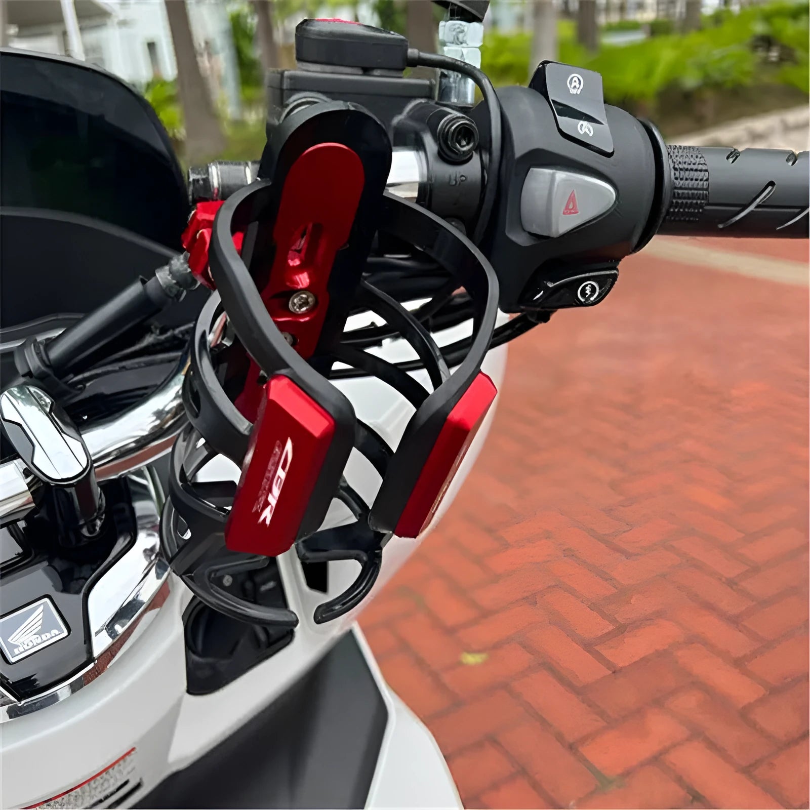 Black modified water bottle cage mounted on a Honda X-ADV scooter bumper.