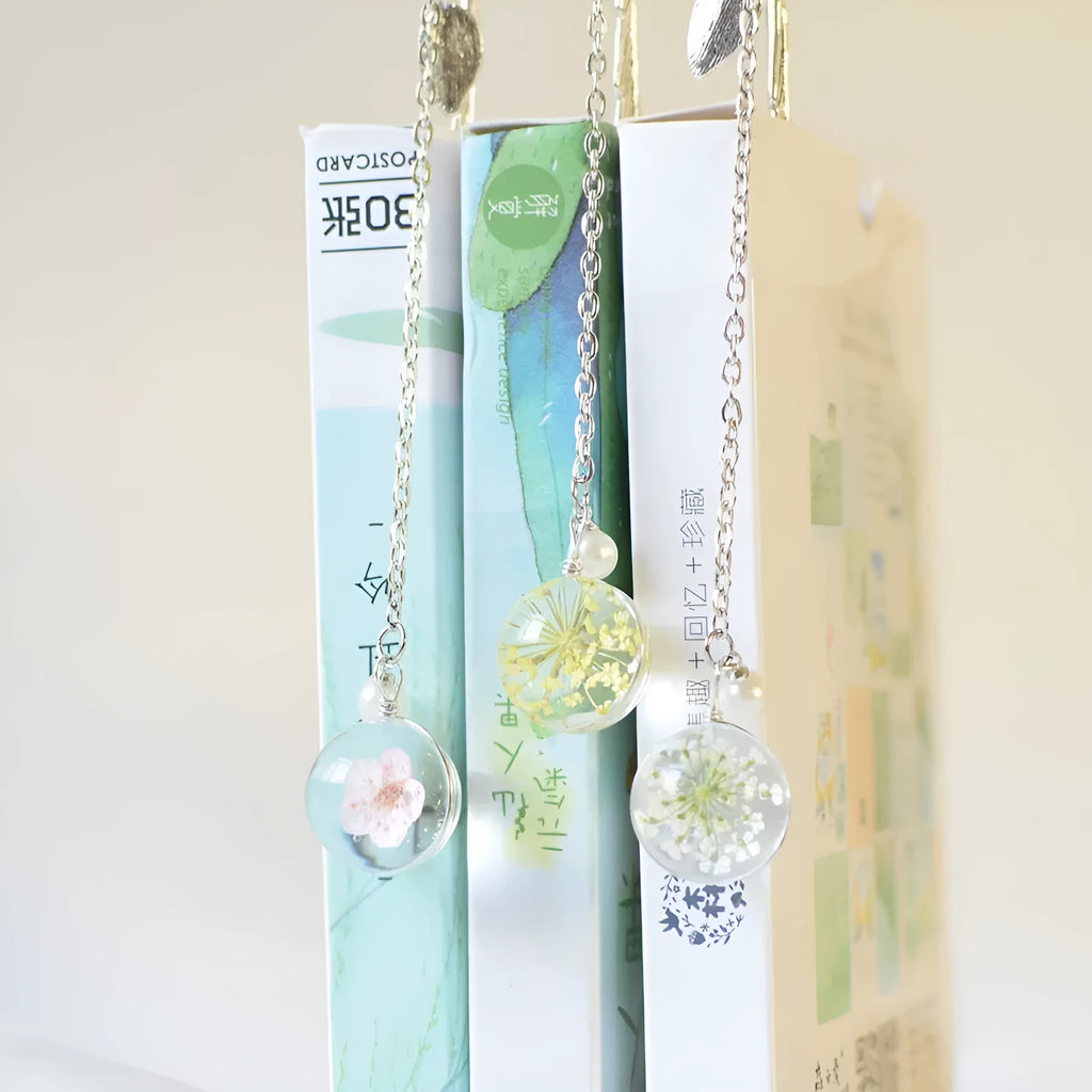 Close-up of a dried flower embedded in a rectangular alloy metal bookmark on an open book.