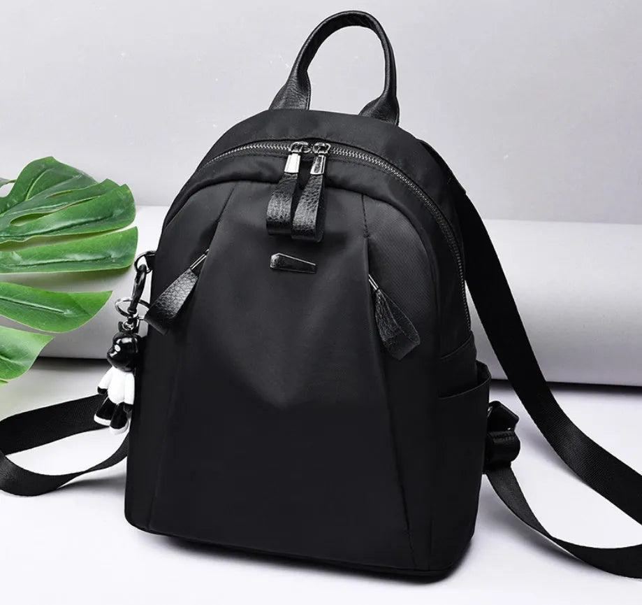 Medium square-shaped wine red Oxford cloth rucksack with double black straps and a soft handle.