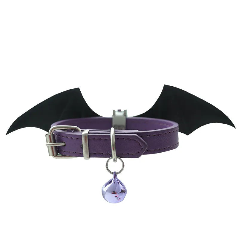Small black patent leather pet collar with silver devil wings charm and bell on a white background.