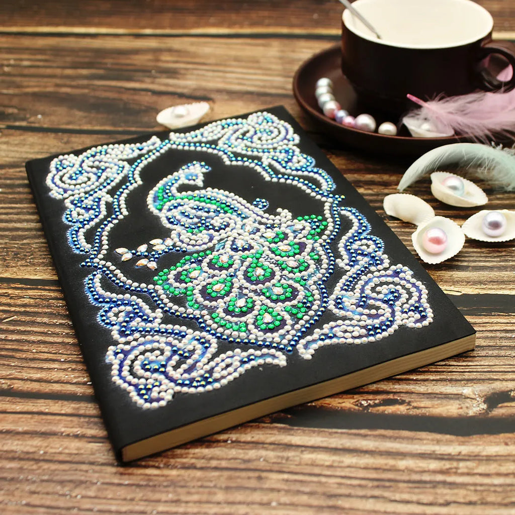 A5 diamond painting notebook kit with peacock design, shaped drills, and bright drills on black cover.