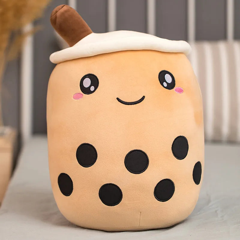 Brown boba milk tea plushie soft toy shaped like a cup with fruit, sitting as a cushion.