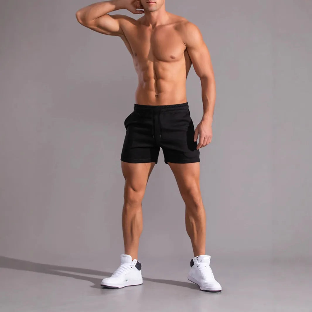 A pack of three men's solid colour drawstring shorts in black, khaki, and light brown, laid flat.