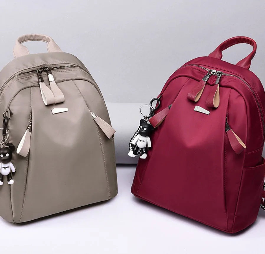 Medium square-shaped wine red Oxford cloth rucksack with double black straps and a soft handle.