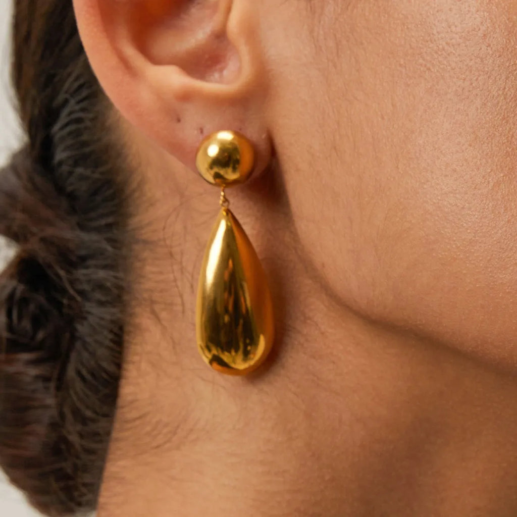 A pair of gold-coloured hemisphere-shaped earrings with a water drop pendant design, made from stainless steel.