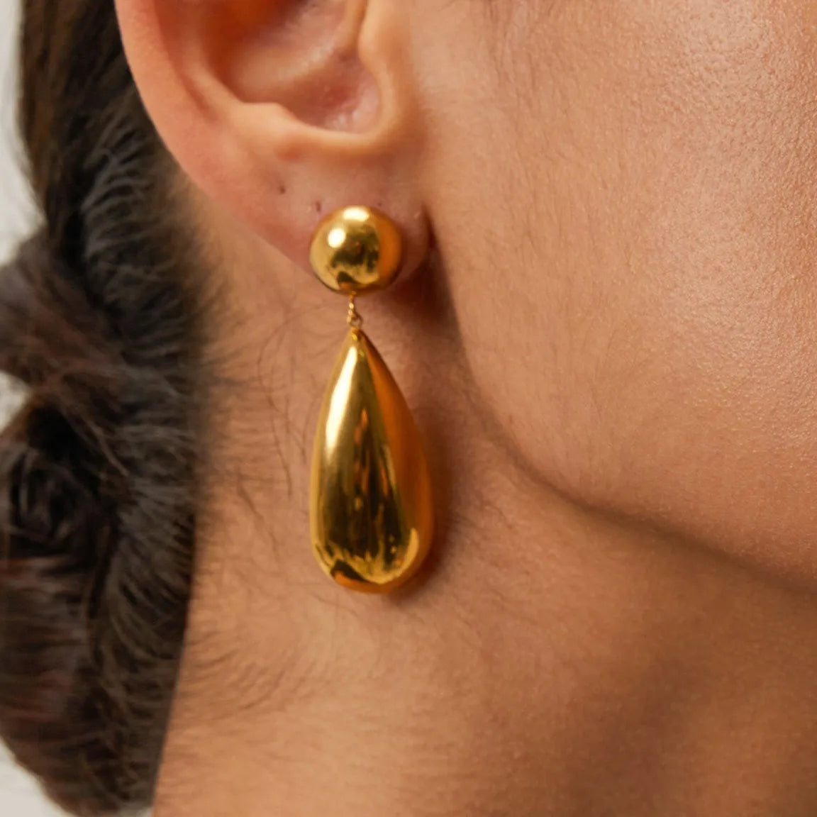 A pair of gold-coloured hemisphere-shaped earrings with a water drop pendant design, made from stainless steel.
