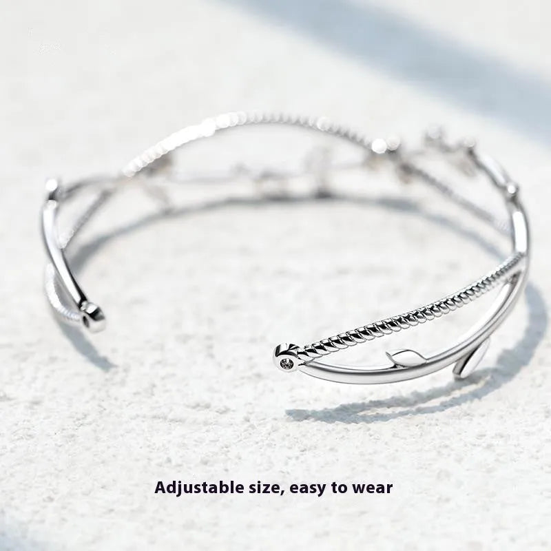 White gold sprout branch bracelet with cross twisted design on a wrist.