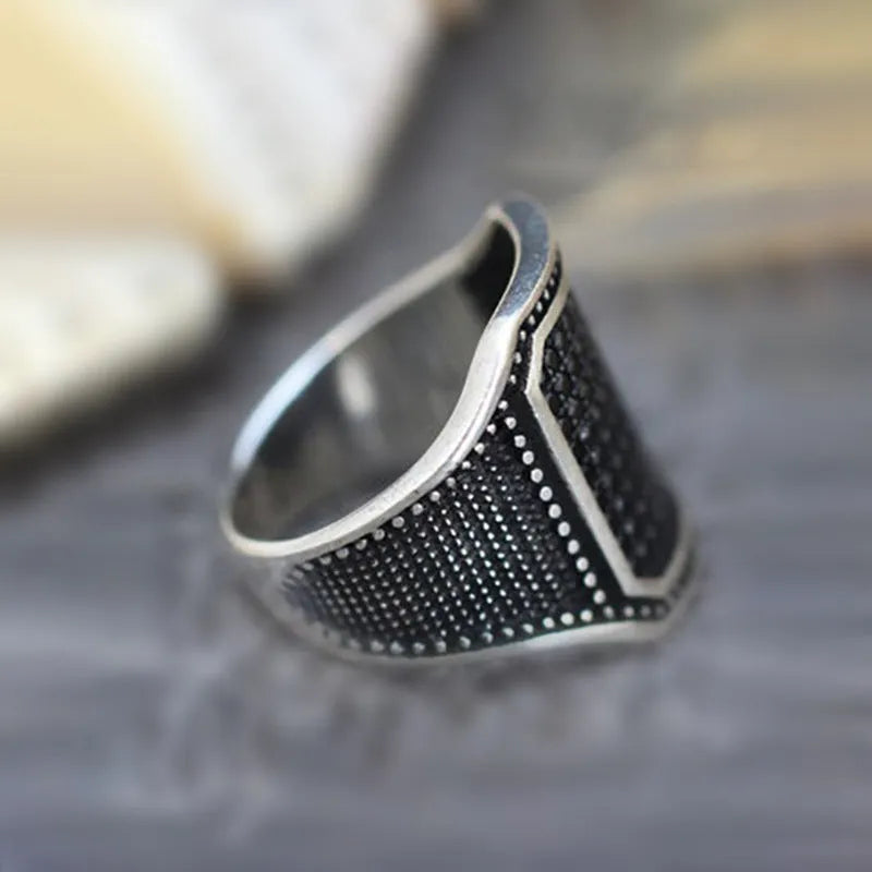 Black alloy ring with a zircon stone set in a copper-coloured inlay, showing a side profile view.